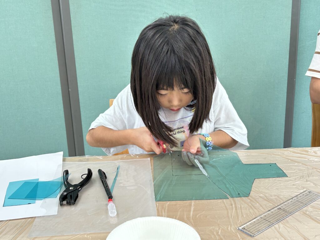 オリジナル転写ポーチ作りに取り組む女の子。専用のシートをはさみでカットすることに集中している様子。