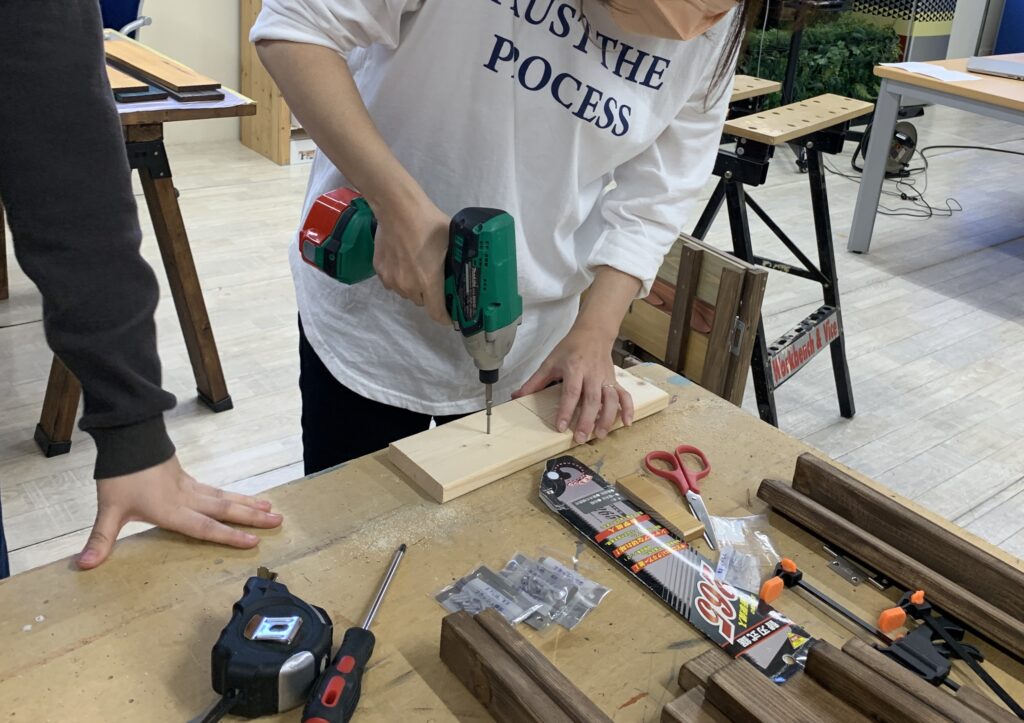 電動ドリルドライバーを用いて木板へ穴あけを行うDIYワークショップの様子