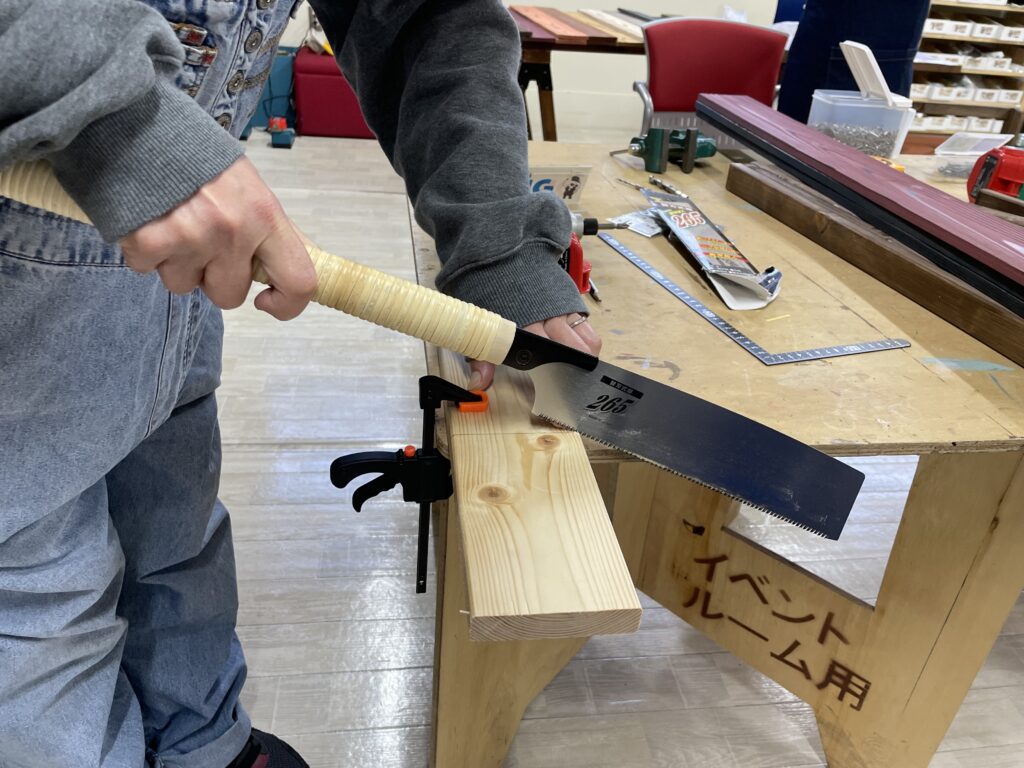 鋸(のこぎり)を使って木材のカット加工を行うワークショップの作業風景