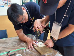 トルクフェスタのシニア向けDIYワークショップでDIYアドバイザーと電動ドライバーを使って木材に穴あけする様子